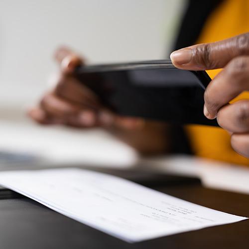 A person takes a picture of a check with their phone.