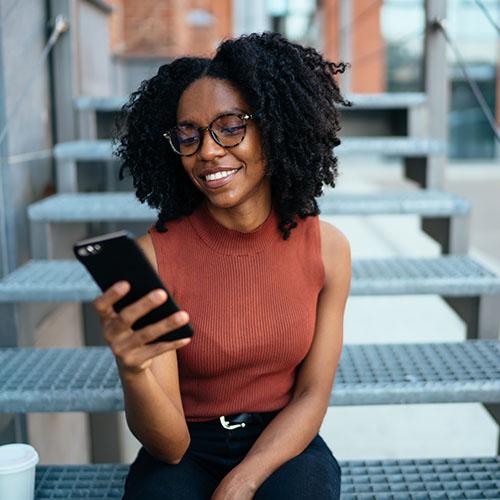A woman sitting on the stairs and looking at her phone.